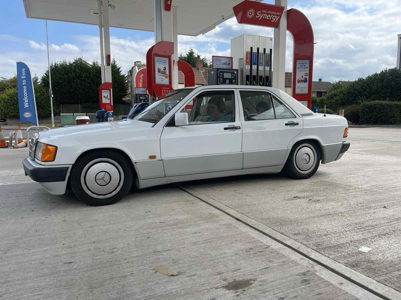 A white Mercedes 190 saloon on a petrol station forecourt