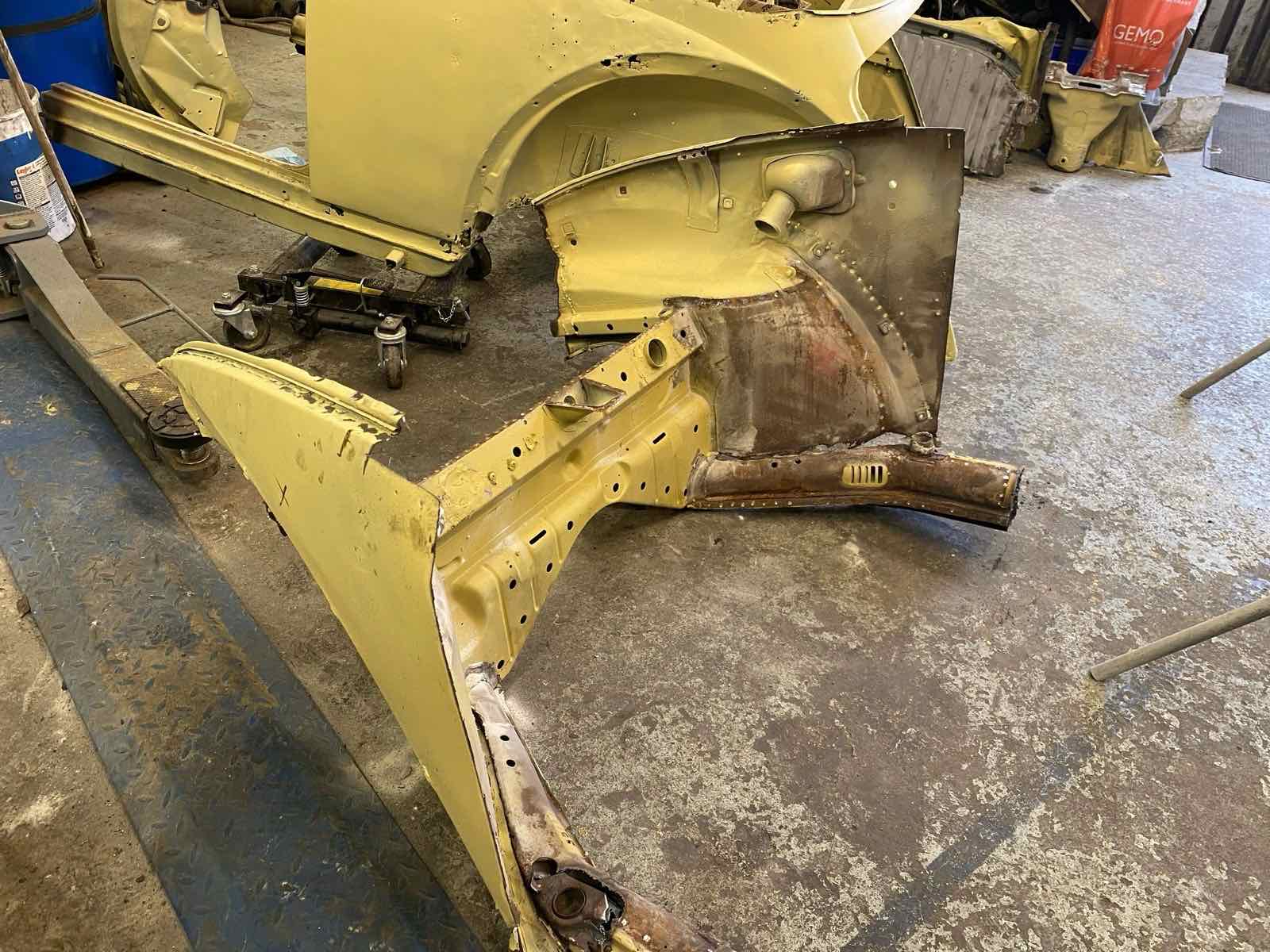 A rusty front quarter and inner wing cut away from a shell in yellow primer