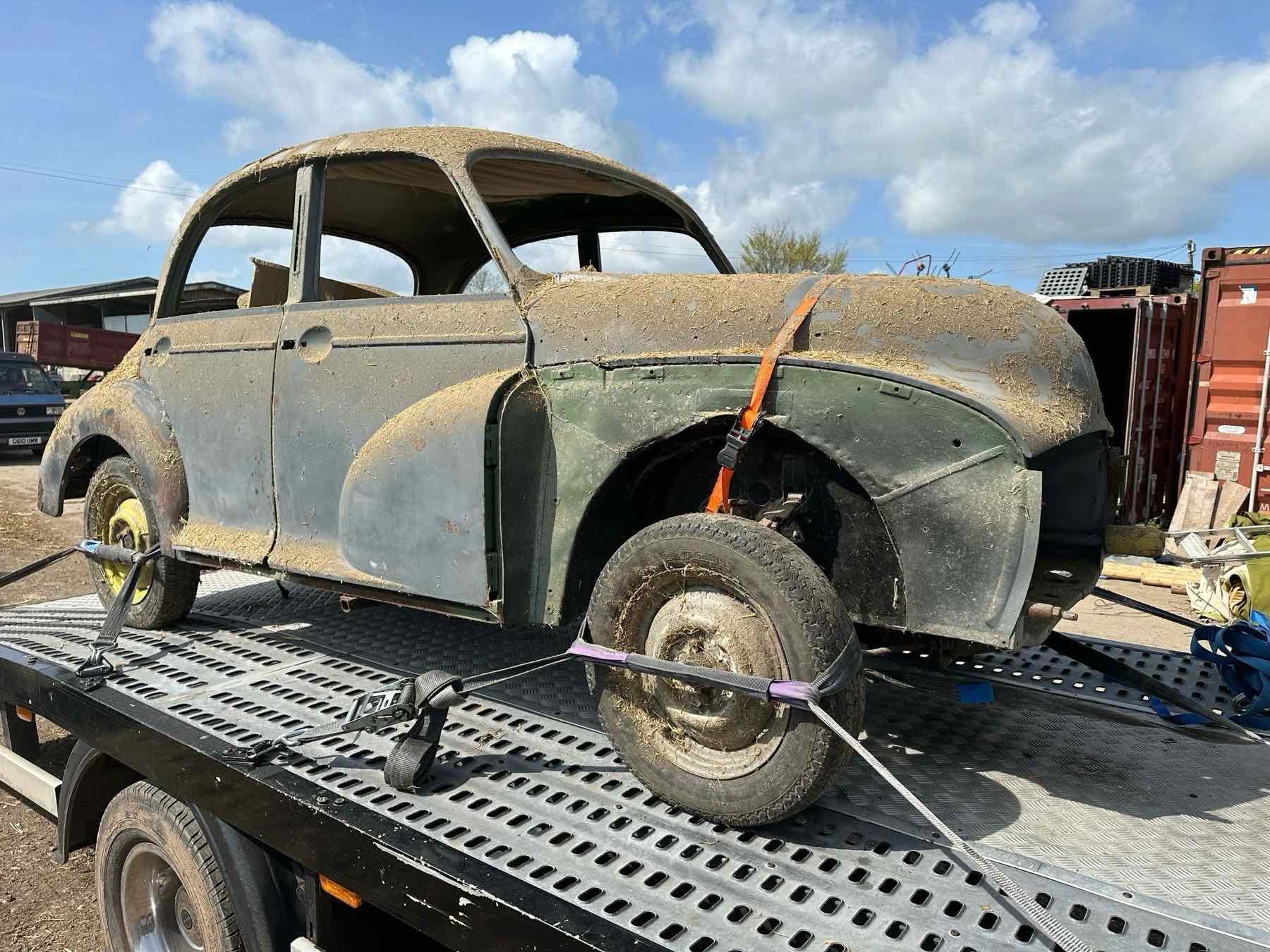 A dirty, weathered Morris Minor strapped onto a recovery truck